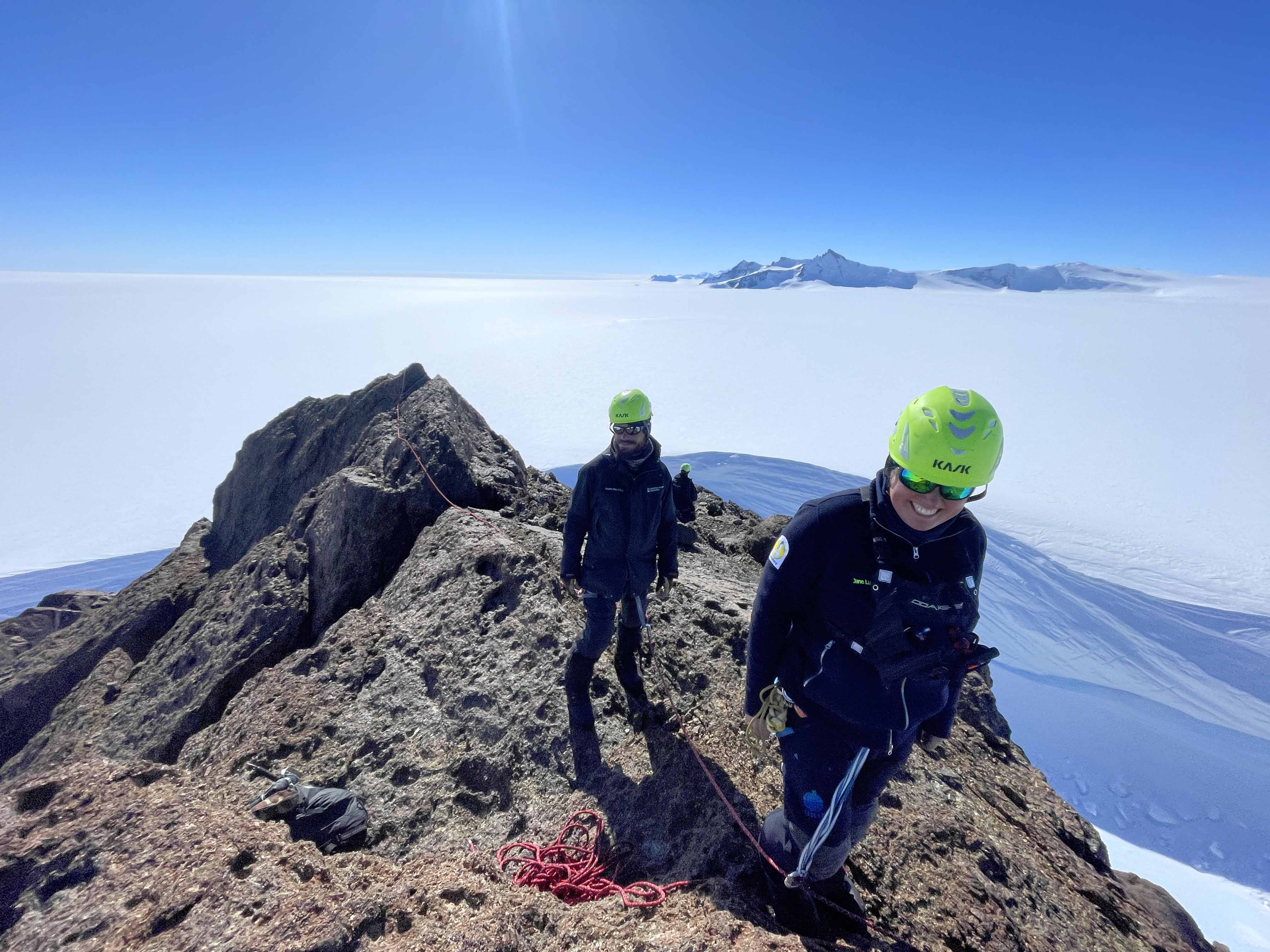 Två personer befinner sig på en bergsrygg inbundna i rep. 