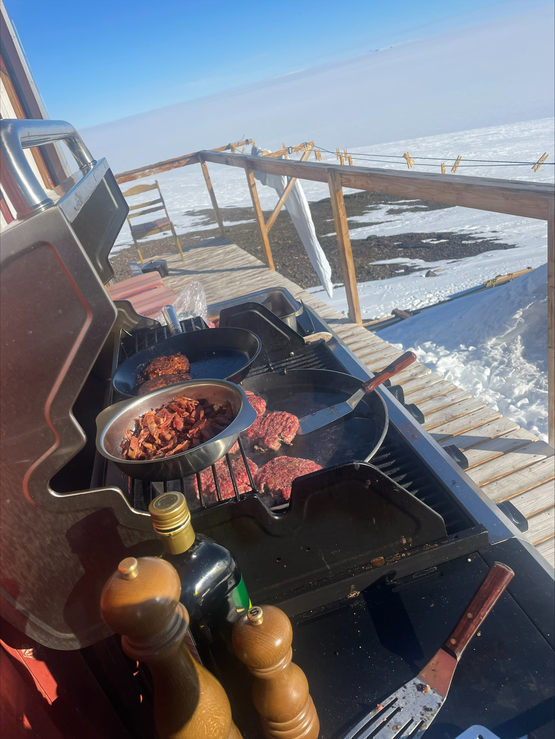 En grill där kött tillagas. I bakgrunden syns de antarktiska vidderna. 