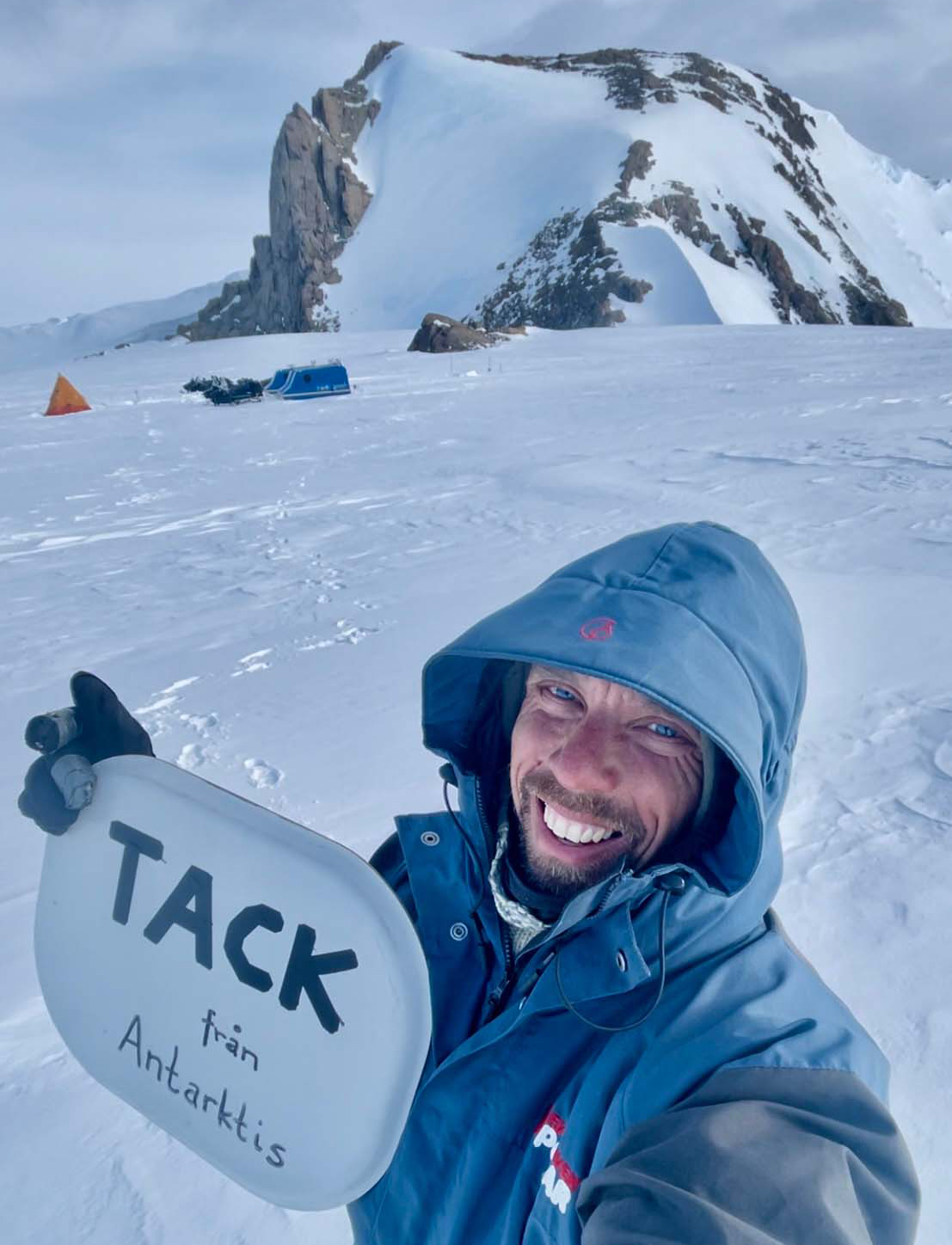 En man håller upp en skylt med texten Tack till Antarktis. 