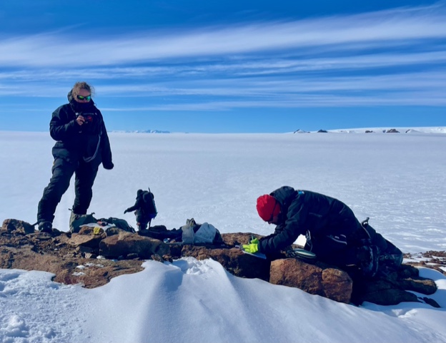 Två personer arbetar på höjden av en bergsrygg. 