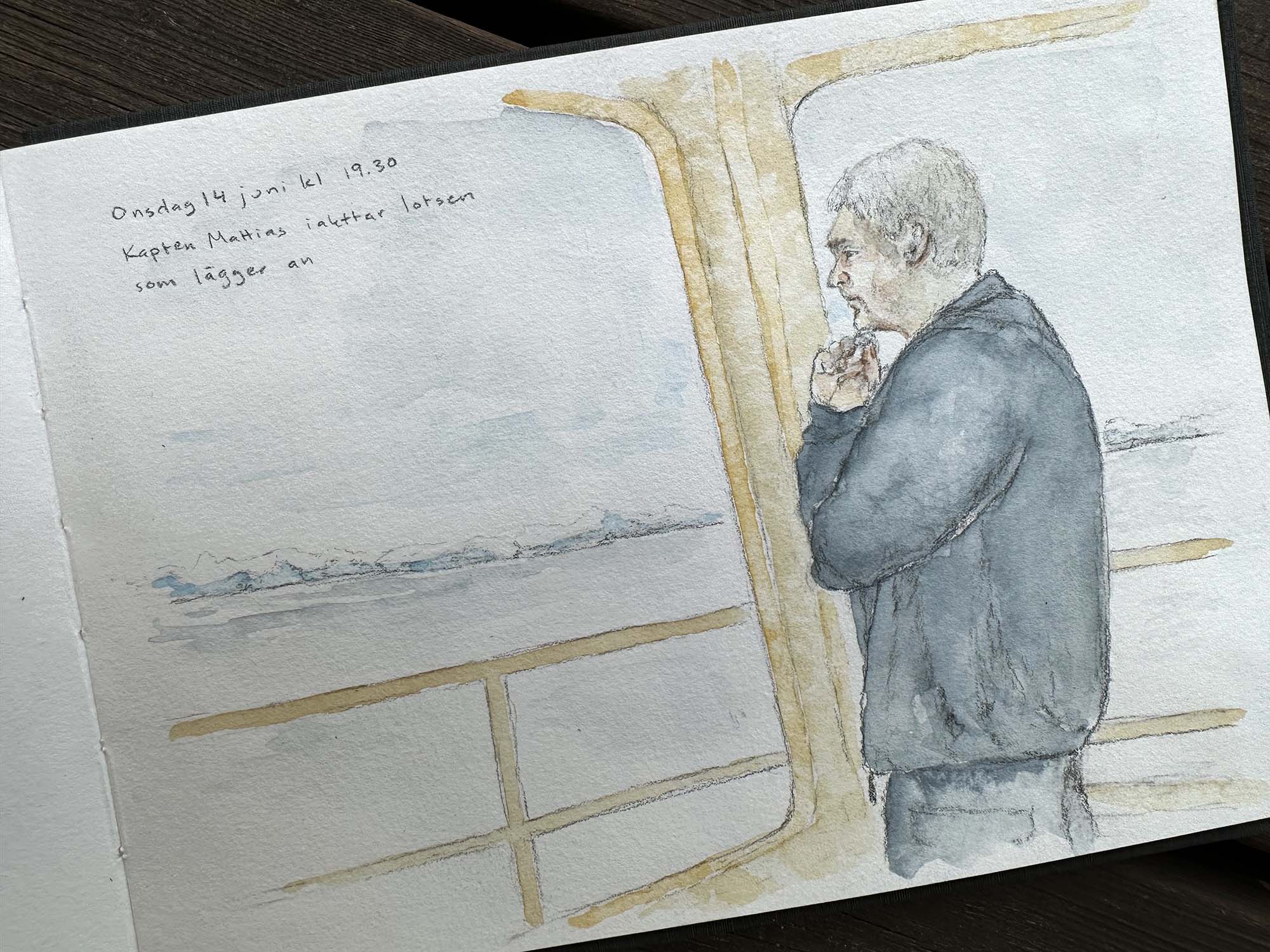 Person i blå kläder håller ena handen under hakan och tittar ut över vattnet