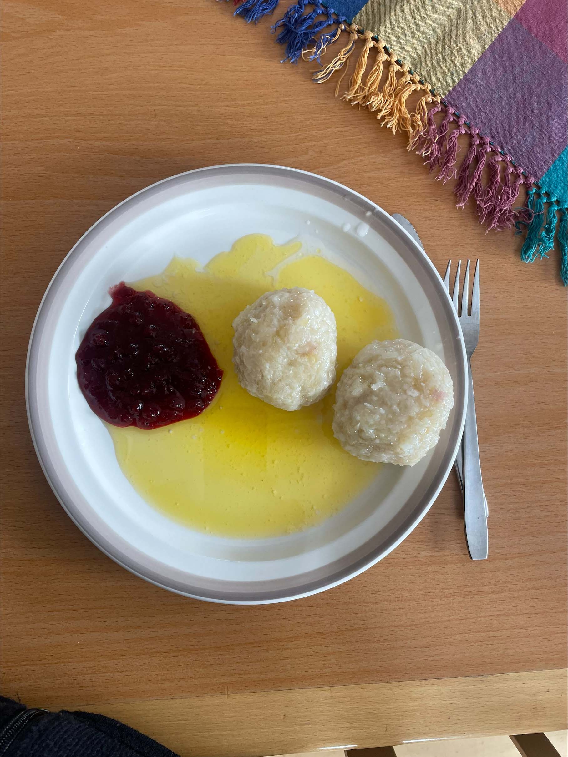 En tallrik med palt, smält smör och röd sylt. 