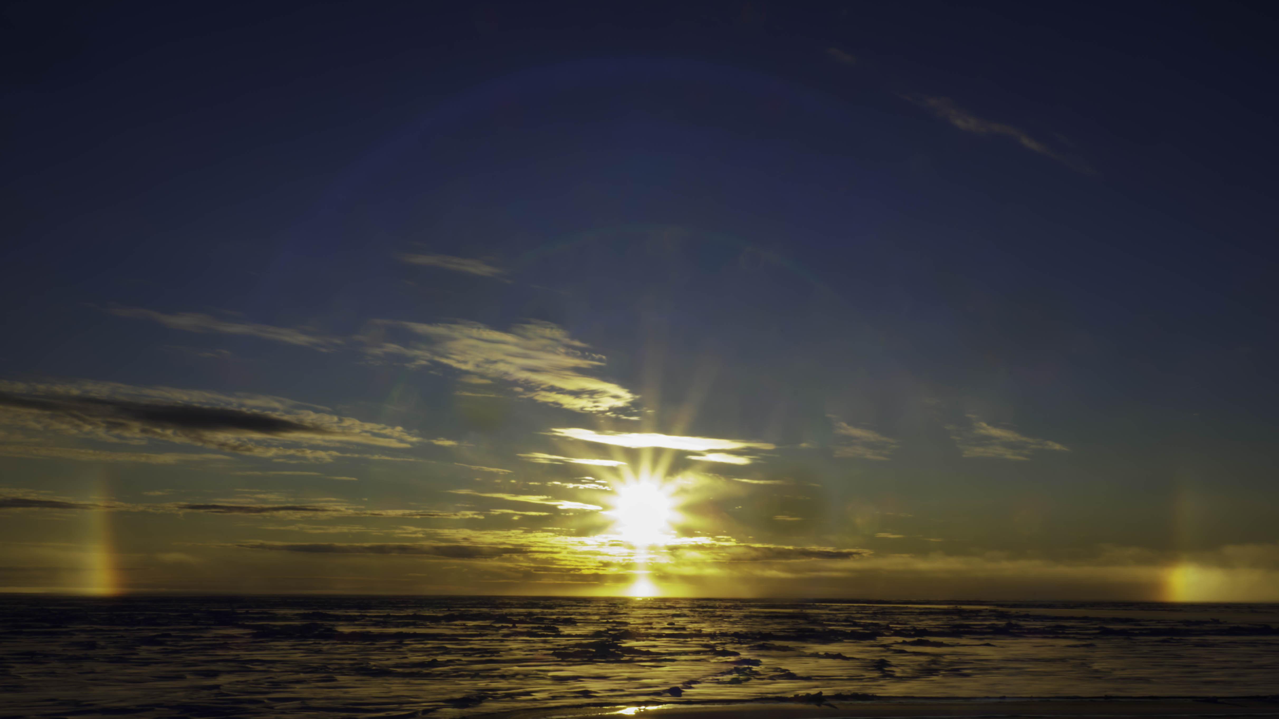 Sol med en dubbel halo (ringar kring solen) och två bisolar på horisonten.