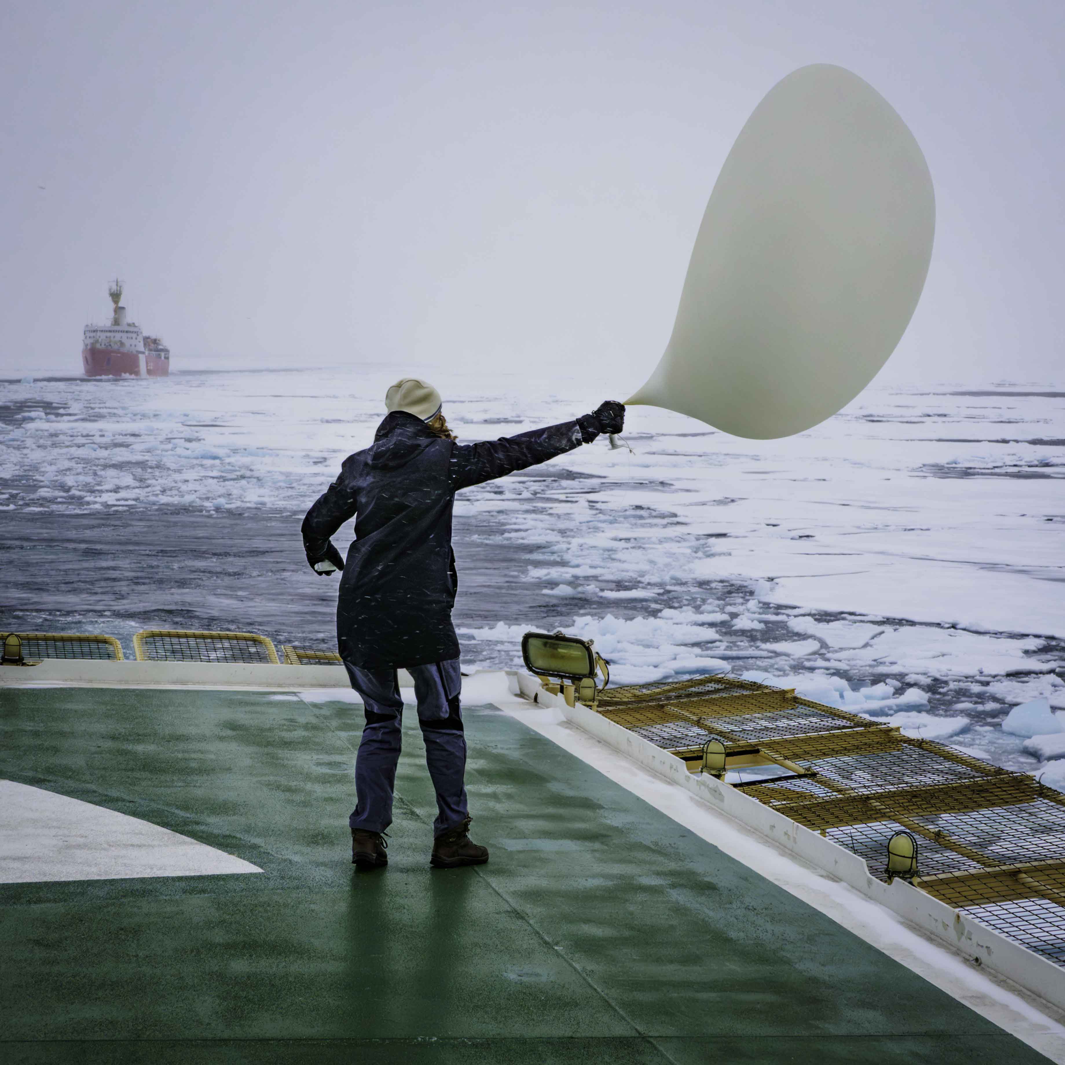 Doktorand som jobbar hårt för att hålla ordning på en radiosondballong på Odens helikopterdäck under en storm i Norra ishavet.